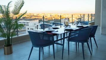 A dining area with a table set for four, chairs, a potted plant, and a city view.