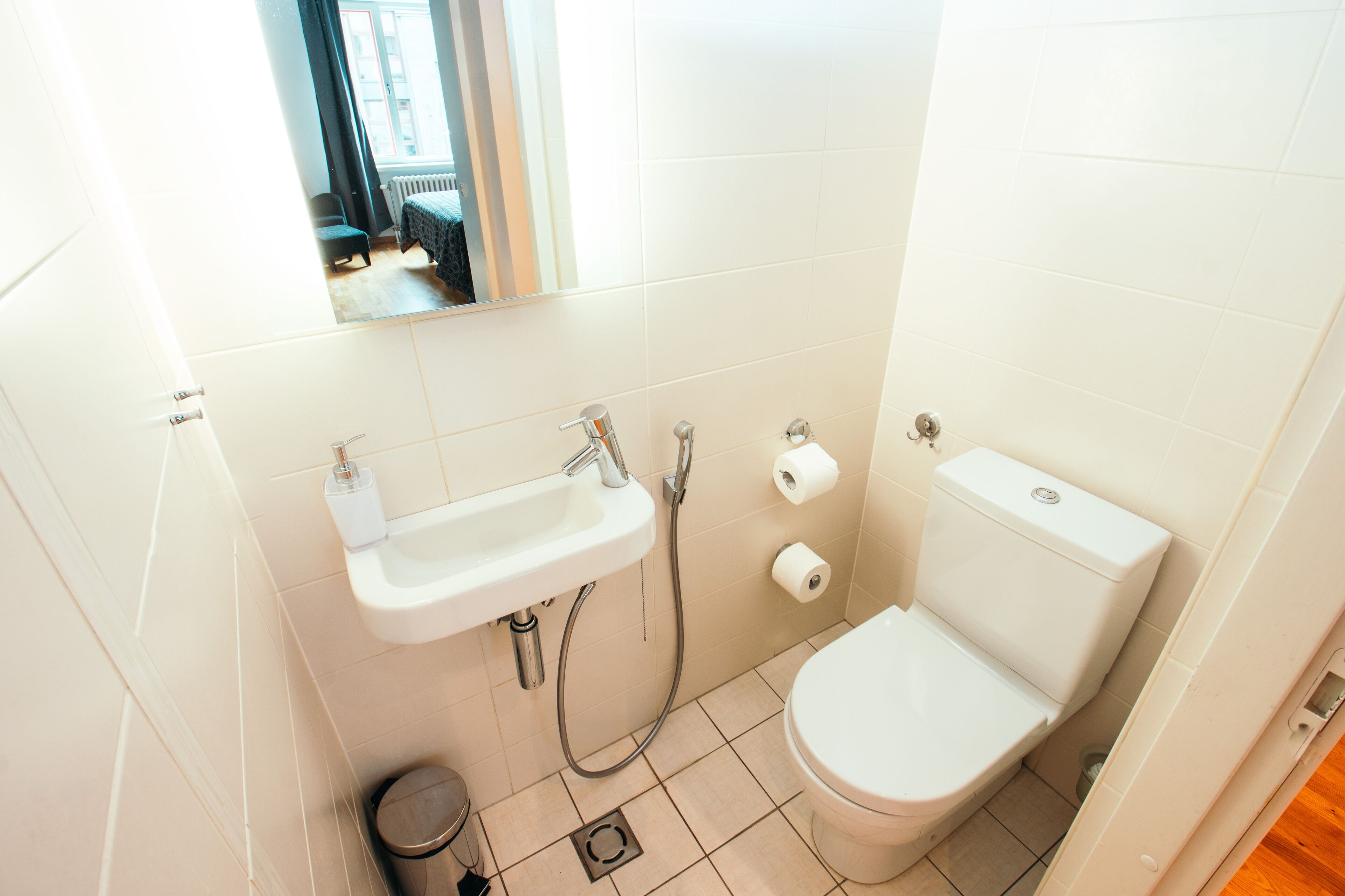 A small, clean bathroom with a toilet, sink, and mirror.
