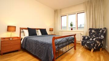 Une chambre à coucher avec un lit en bois, une table de chevet, une chaise et une fenêtre donnant sur un beau paysage.