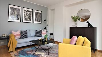 Una sala de estar moderna con un sofá, una mesa de centro, un sillón amarillo y un mueble de madera oscura.