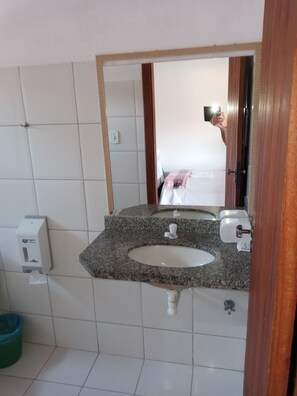 A bathroom with a granite countertop sink, a mirror, and a hand soap dispenser. - Pousada Olhar da Sereia (Porto Seguro)