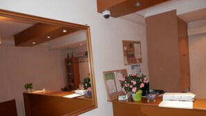 A reception desk with a mirror, a bulletin board, and a potted plant with pink flowers. - Shamrock Guest House (Gravesend)