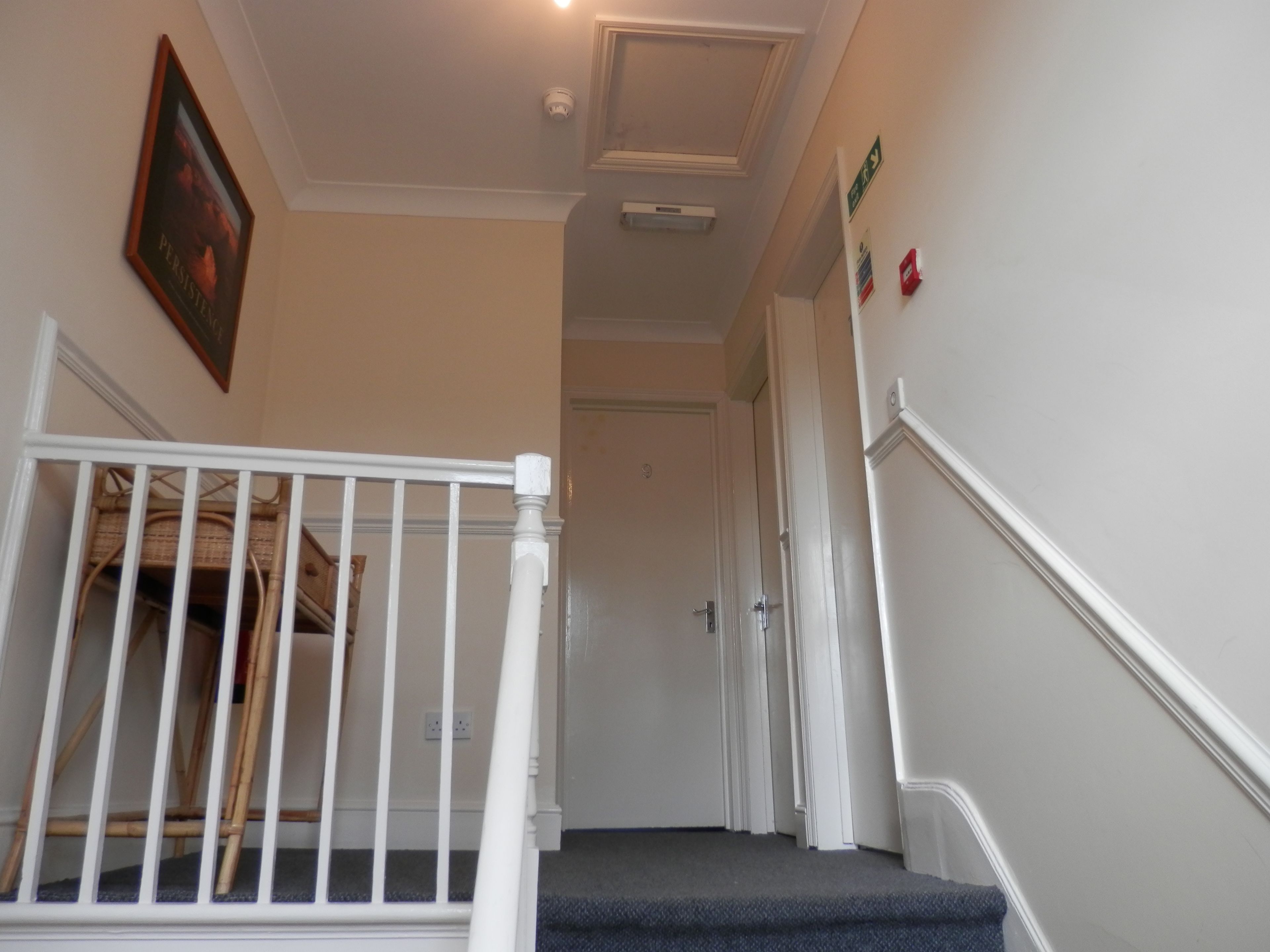 Un escalier avec une rampe blanche menant à une porte.