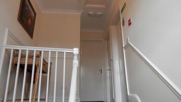 Un escalier avec une rampe blanche menant à une porte.