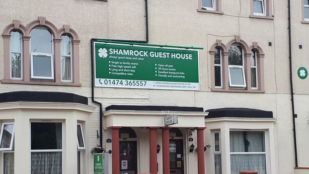 A Shamrock Guest House with a green signboard listing features like single to family rooms, free high-speed wifi, and 24-hour access. - Shamrock Guest House (Gravesend)