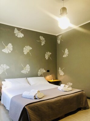 A hotel room with a bed, a nightstand, a lamp, and wall art. - Guest house 296 (Verona)