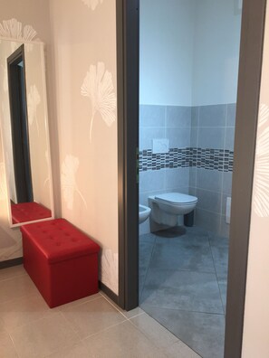 A bathroom with a toilet, a bidet, and a red bench. - Guest house 296 (Verona)