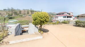 A residential area with a large house, a tree, and a dirt road. - GuestHouser 4 BHK Homestay f531 (Devikolam)