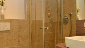 A modern bathroom with a glass-enclosed shower, a white toilet, and a vanity with a mirror.