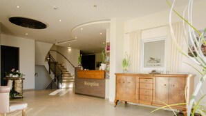 A reception area with a wooden reception desk, a staircase, and a cabinet with drawers. - Gasthof Robben (Twist)