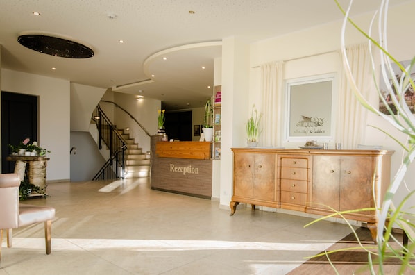 A reception area with a wooden reception desk, a staircase, and a cabinet with drawers. - Gasthof Robben (Twist)