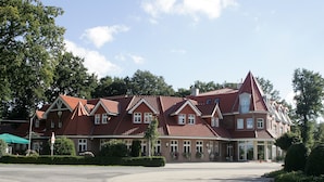A large, red-roofed building with multiple windows and a prominent tower. - Gasthof Robben (Twist)