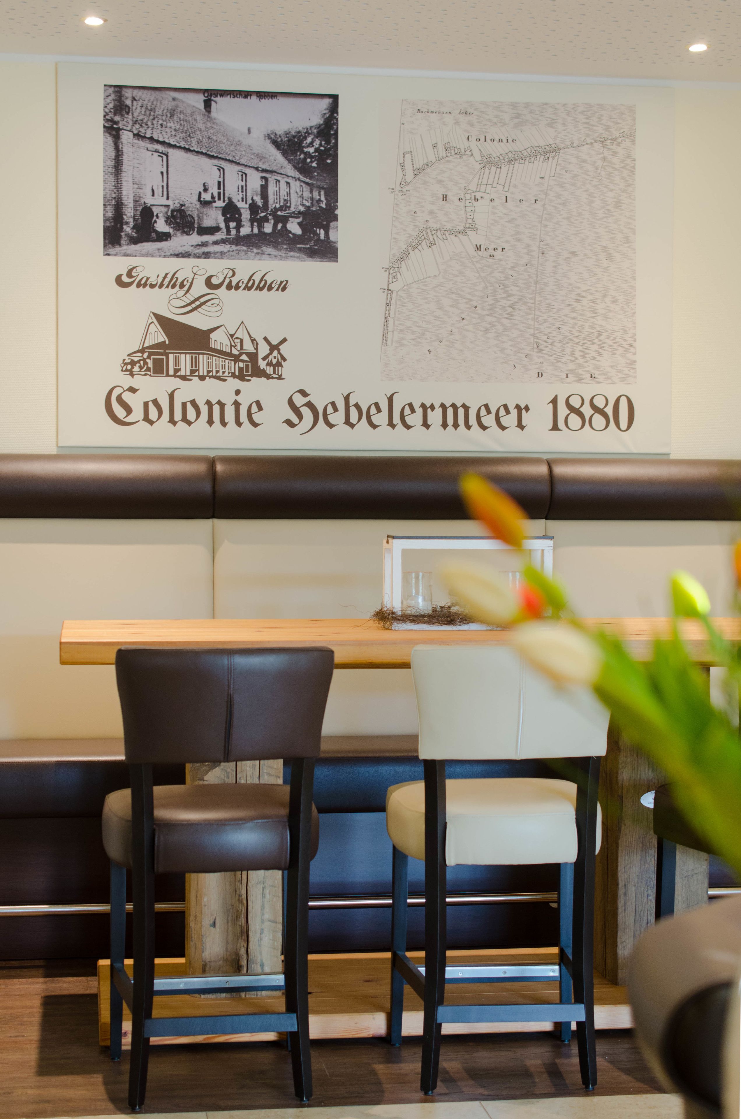 Interior de restaurante con un mapa antiguo y una fotografía en la pared, mesas y sillas de madera.