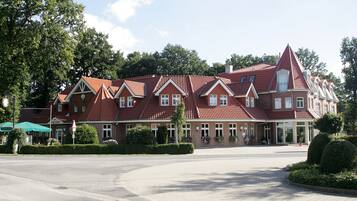 Stately building with a traditional European design, surrounded by lush greenery and a well-manicured entrance.