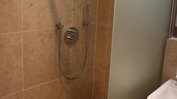 A modern bathroom with a glass shower enclosure, a handheld showerhead, and a towel rack.