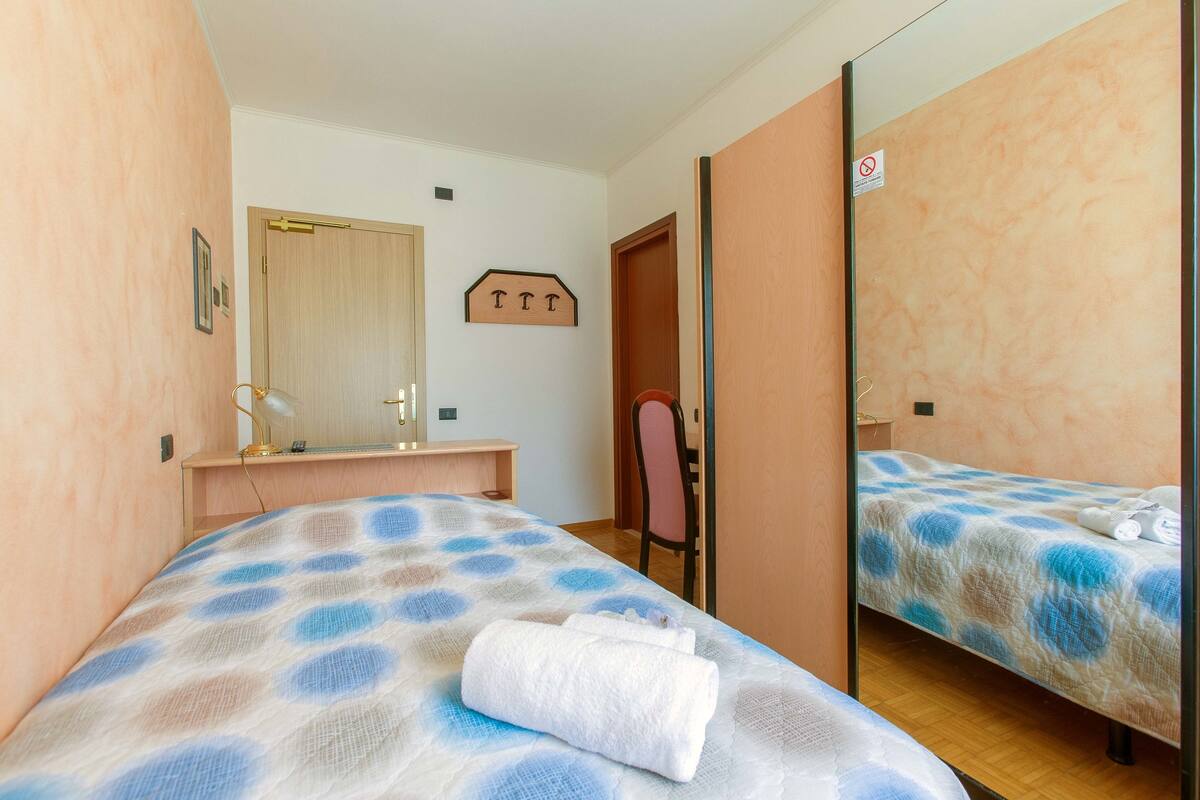 Une chambre à coucher avec un lit, un bureau, une chaise et un miroir.