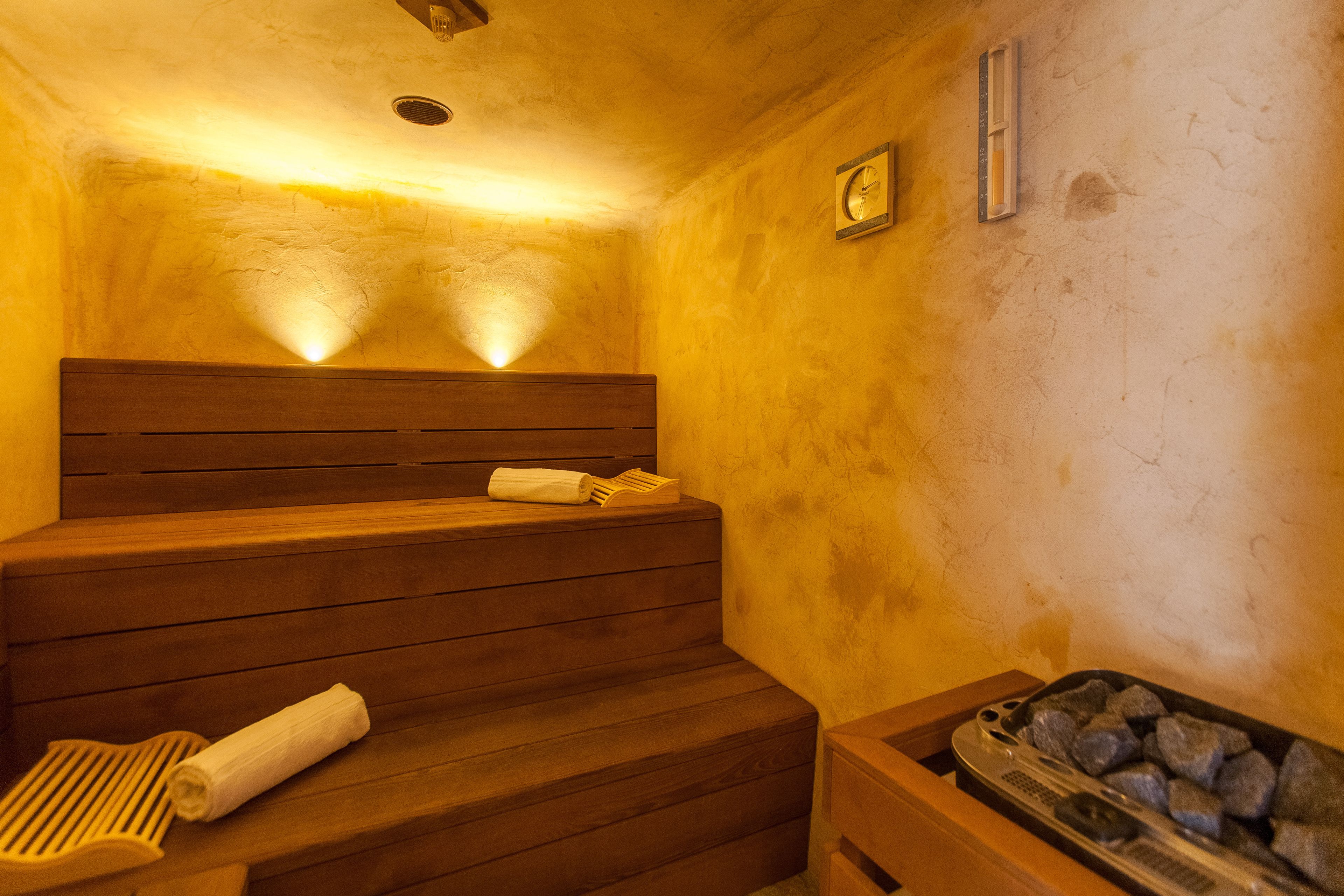 Una sauna con panche di legno, un asciugamano e un vassoio di pietre.