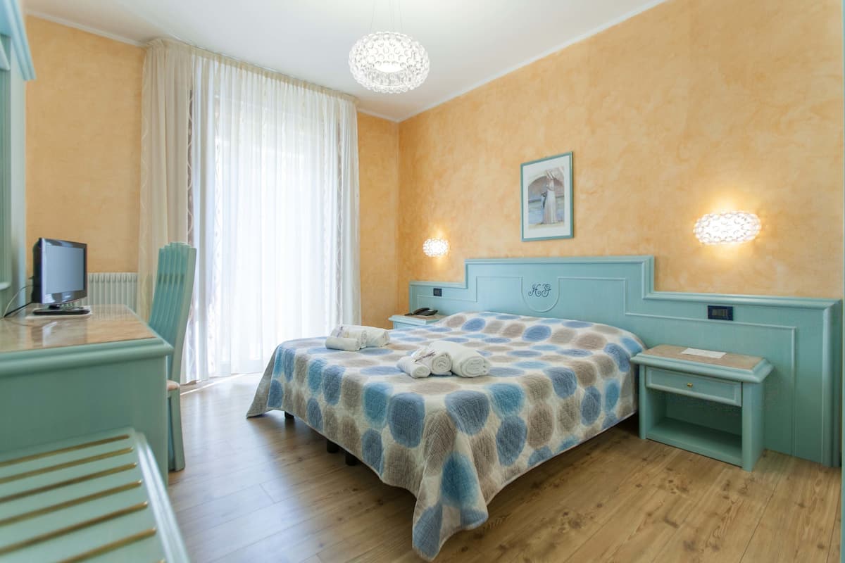 Une chambre d’hôtel comprenant un lit, un bureau avec un ordinateur, une chaise et une table de chevet.