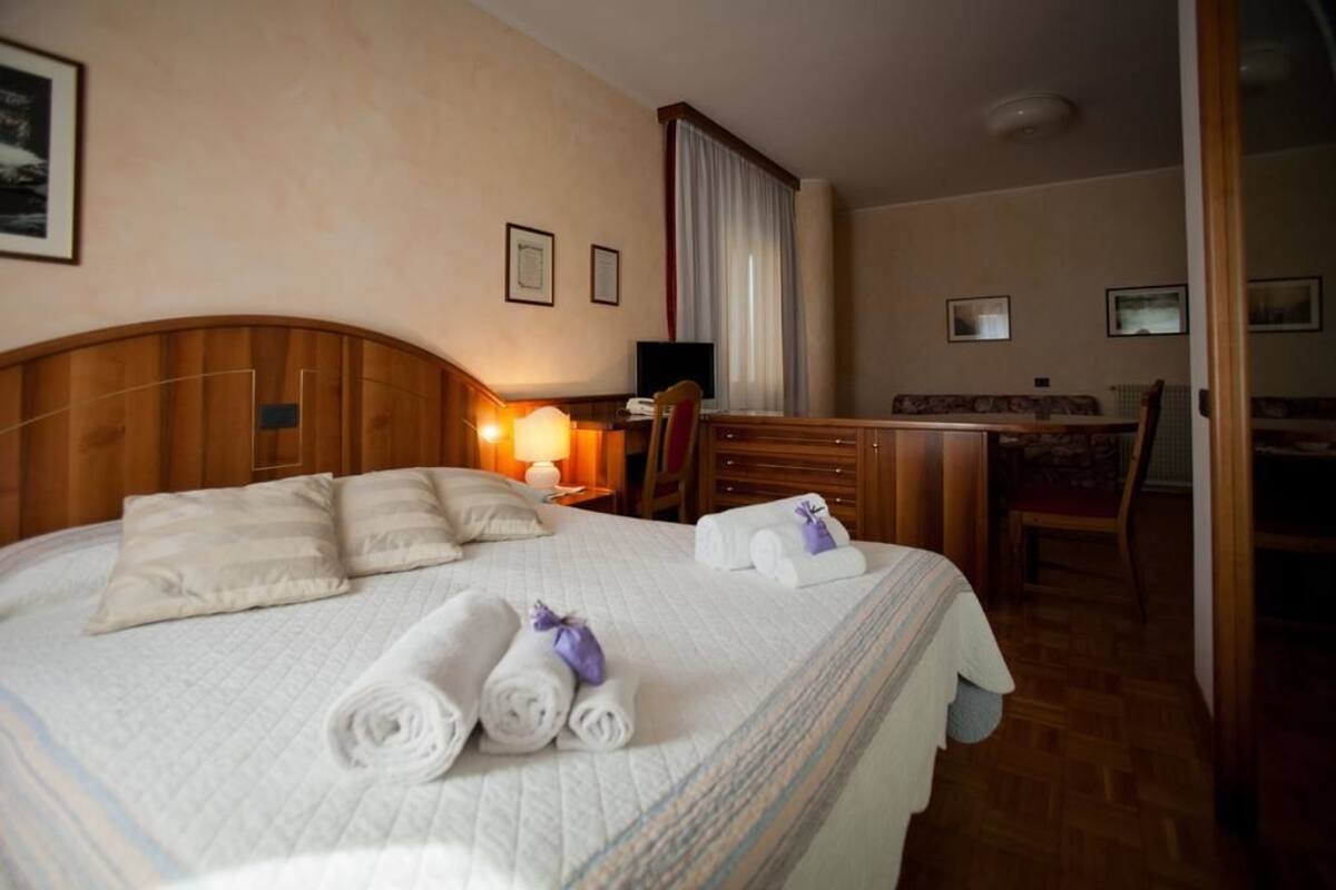Une chambre d’hôtel avec un grand lit, un bureau avec une chaise et un petit coin salon.
