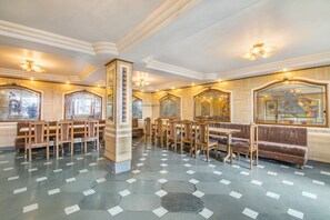 A spacious lobby with hexagonal patterned flooring, wooden furniture, and artwork on the walls.