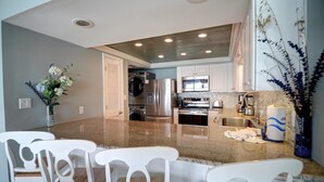 A modern kitchen with granite countertops, stainless steel appliances, and white cabinetry. - Beach House Condos by Crystal Waters (Destin)