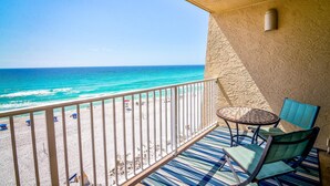 A balcony with a view of the beach and ocean, a table, and two chairs. - Beach House Condos by Crystal Waters (Destin)