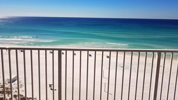 A beach view with a railing in the foreground. - Beach House Condos by Crystal Waters (Destin)