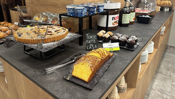 A buffet counter with various desserts including a large cake, muffins, and a sign indicating 'Torte Fatte Casa'. - Hotel Ferrari (Pinzolo)
