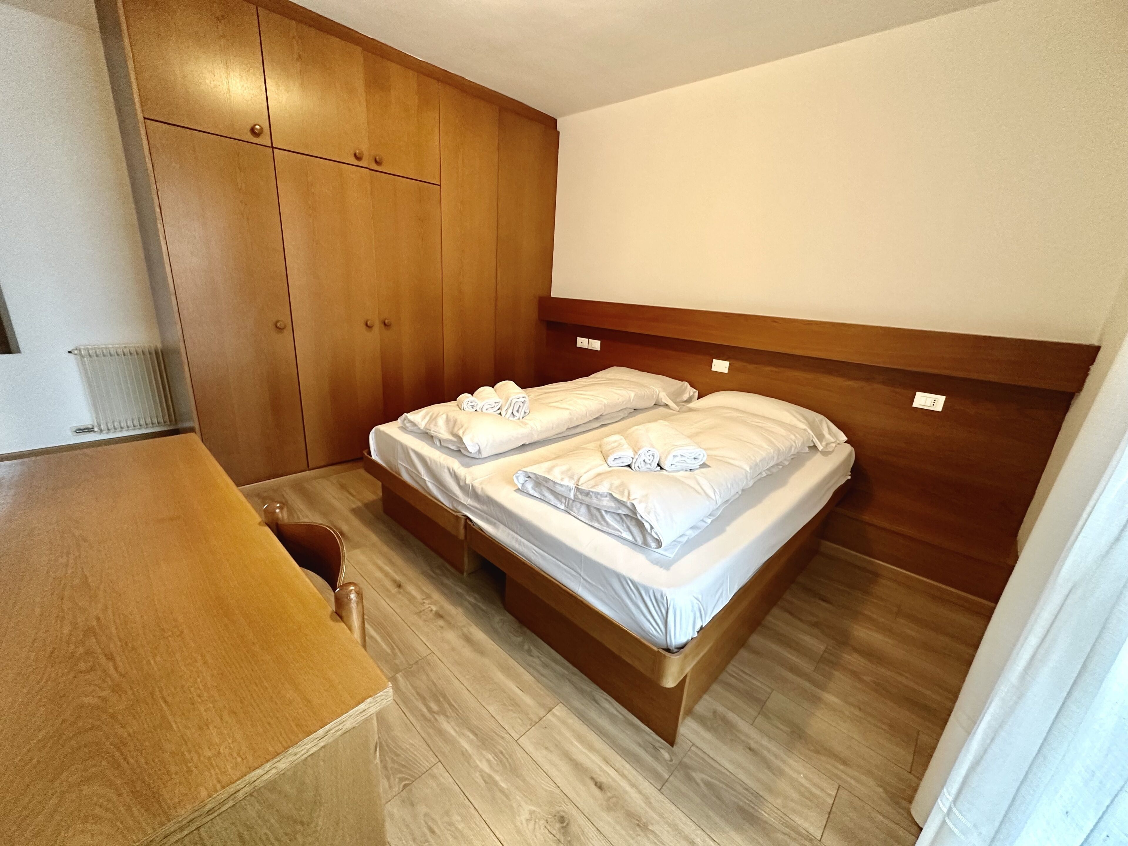 Habitación de hotel con dos camas, piso de madera, cabecera de madera y escritorio de madera.
