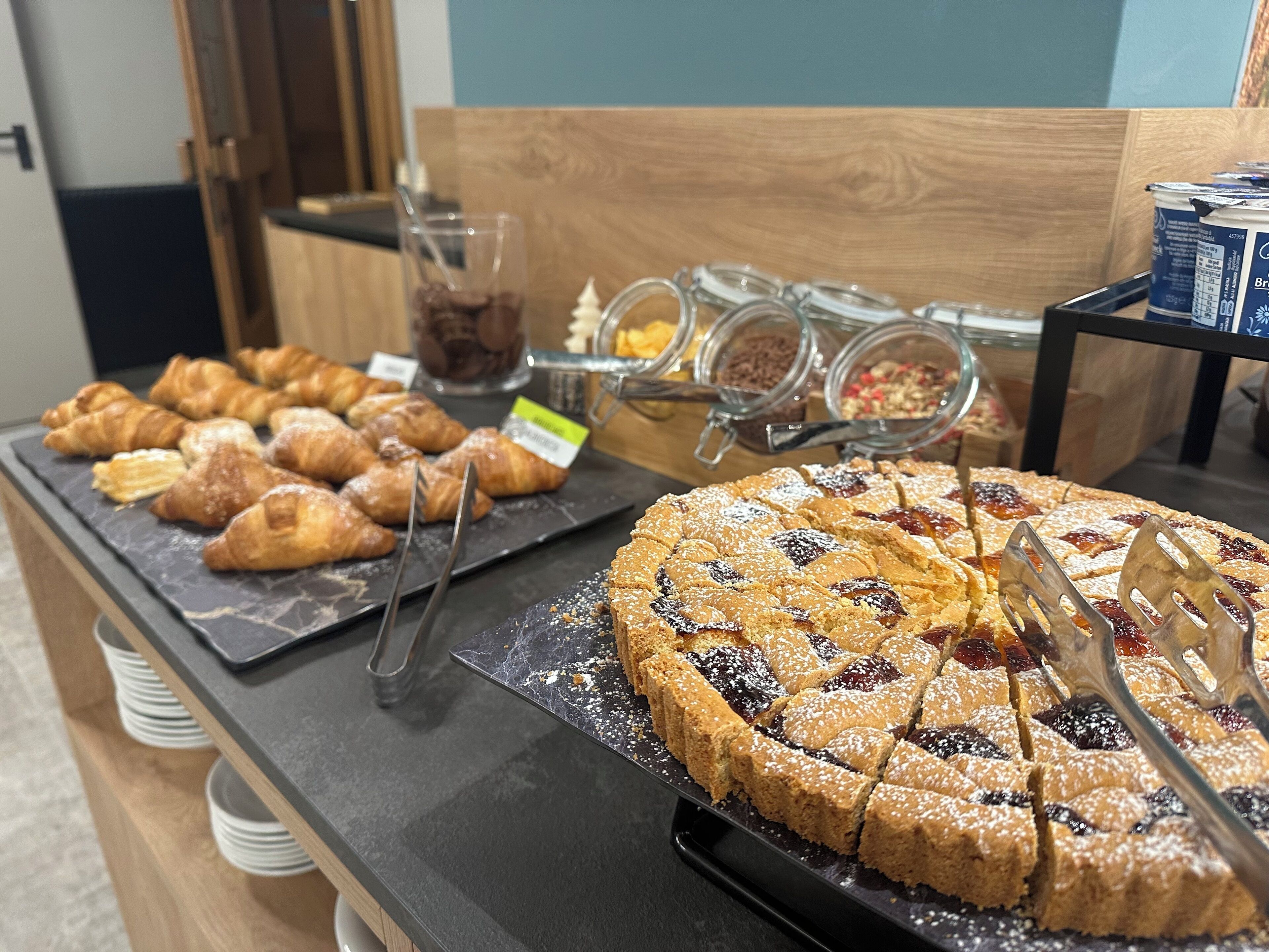 Un bufé con pasteles, una tarta grande de frutas y diferentes salsas.