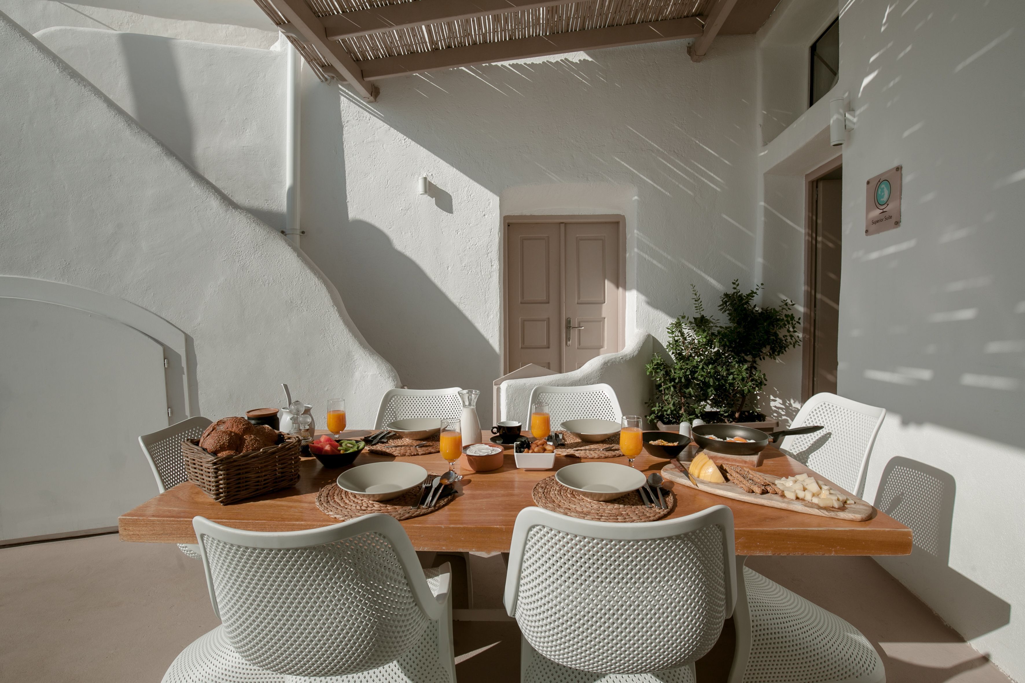 A breakfast table set with white chairs, a wooden table, and various breakfast items.