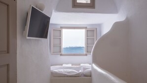 Een smalle trap die leidt naar een bed met uitzicht op zee door een raam.