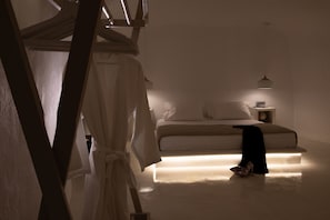 A minimalist bedroom with a bed, bedside table, and a hanging light fixture.