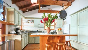 A kitchen with wooden bar stools, a central island, and green cabinets. - Casa Paxanax (Santa Cruz La Laguna)