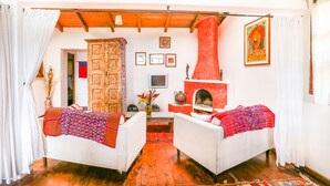 A cozy living room with two white sofas, a wooden cabinet, a fireplace, and a red accent wall. - Casa Paxanax (Santa Cruz La Laguna)