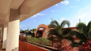 A covered outdoor area with a curved architectural feature, palm trees, and a building with a sign that reads "CASA 11".