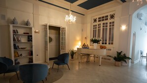 Un salon spacieux avec un piano, une bibliothèque et un lustre.