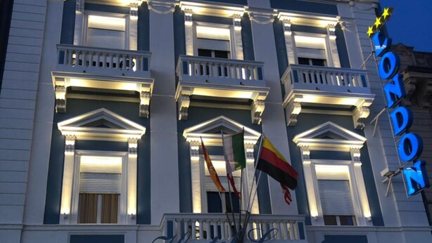 Un hôtel à la façade classique, doté de nombreux balcons et orné de drapeaux.