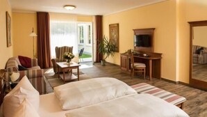 A hotel room with a bed, a desk, a chair, a sofa, and a television. - Hotel Knorre (Meissen)