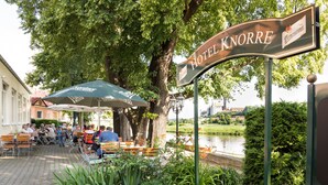 A hotel sign, outdoor seating, and a river view. - Hotel Knorre (Meissen)