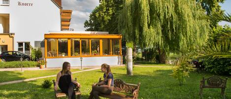 A bench in a grassy area with a building labeled "Hotel Knorre" in the background.