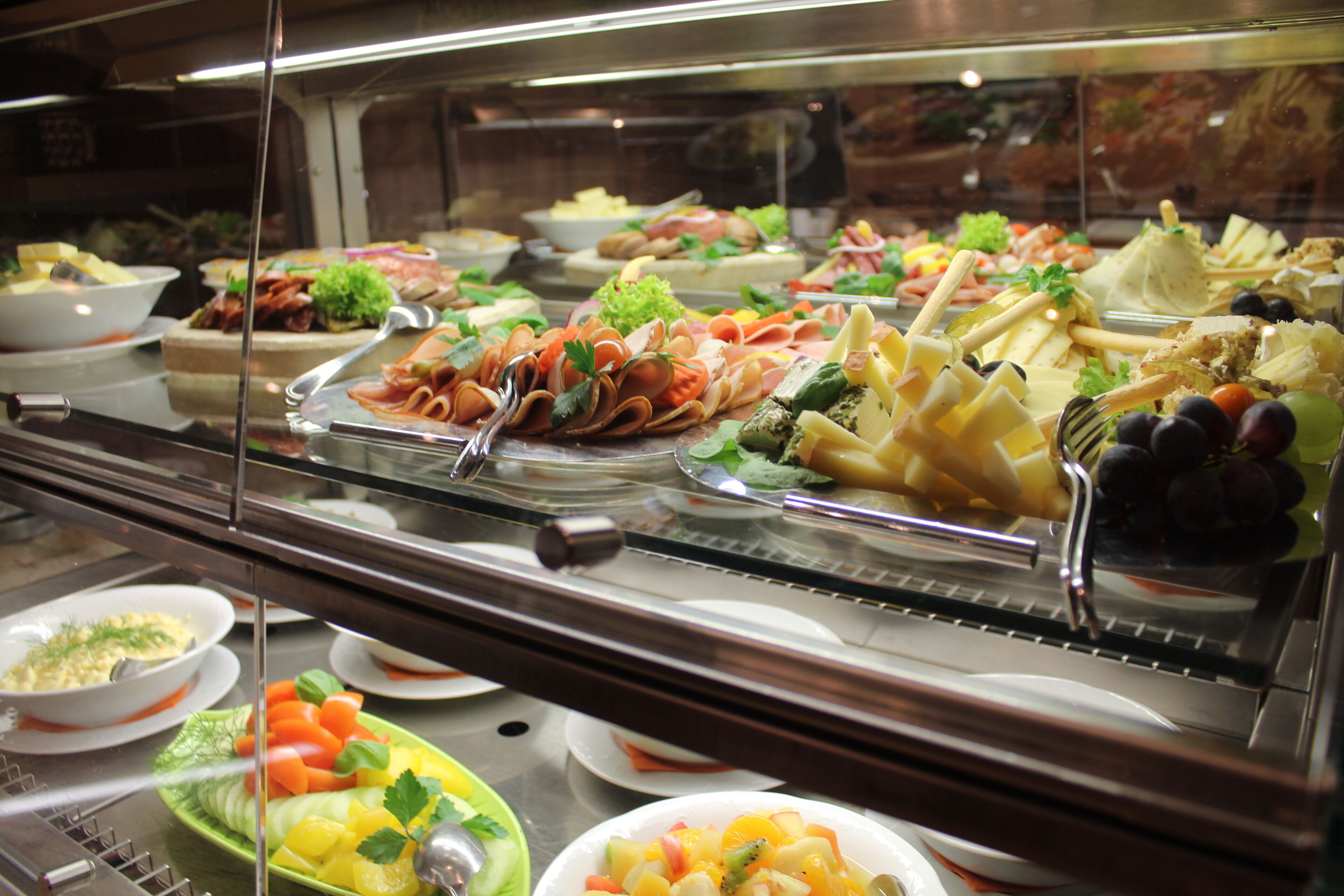 A buffet with various food items including meats, cheeses, fruits, and vegetables.