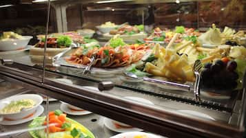 A buffet with various food items including meats, cheeses, fruits, and vegetables.