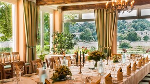 A dining room with a long table set for a meal, large windows with curtains, and a chandelier. - Hotel Knorre (Meissen)