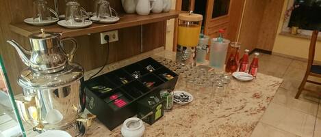 A kitchen with a coffee maker, tea set, and various bottles.