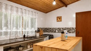 A modern kitchen with a wooden island, a gas stove, and a tiled backsplash.