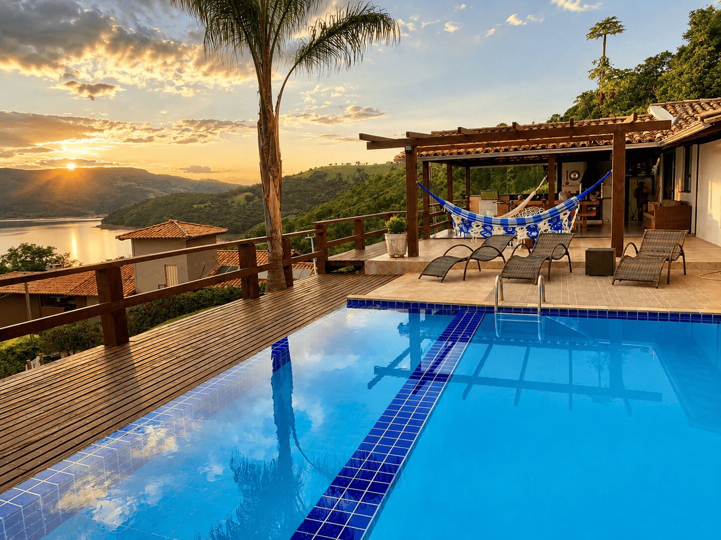 Une piscine avec une terrasse en bois, des chaises longues et un hamac.