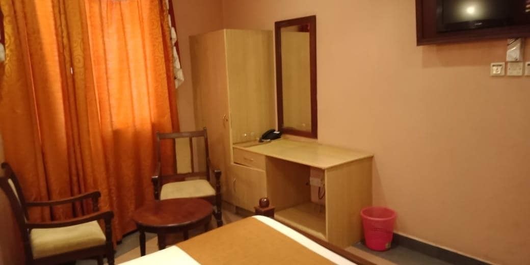 Hotellihuone, jossa on sänky, työpöytä, tuoli, vaatekaappi, peili ja televisio.