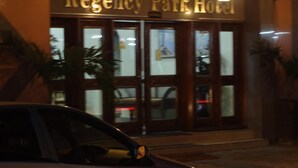Exterior del Hotel Regency Park con un automóvil oscuro estacionado frente al hotel.