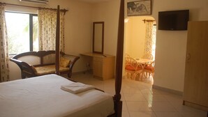 Una habitación de hotel con cama, escritorio, silla, televisor y armario.